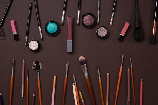 Various cosmetics and brushes on brown background. Top view. Still life. Copy space