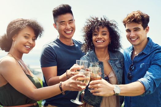 Portrait of a group of friends having drinks and sharing a toast together outside while on holiday.