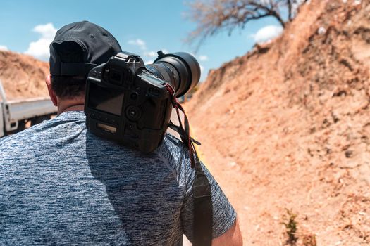 Unrecognizable photographer walking down a dirt path in search of landscape photography.