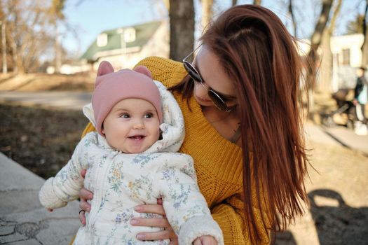 Mother holding baby smiling to camera. Real life authentic casual mom looking to camera holding infant