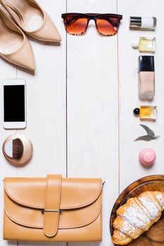 Flat lay, top view, mock up women's clothes and accessories on a white background. phone, shoes, perfume, sunglasses, croissant