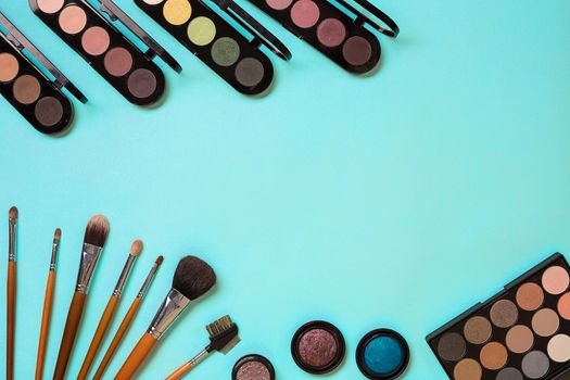 Make up essentials. Set of professional make up brushes, creams and shadows in jars on blue background. Place for your text or logo. Ideal for beauty blog.