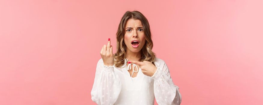 Close-up portrait of shocked and upset, displeased blond girl complaining friend on boyfriend didnt made proposal, pointing at finger without wedding ring, want get married.