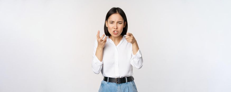 Image of angry pissed off woman shaking from anger, clench hands and grimacing furious, annoyed and outrated, standing over white background.