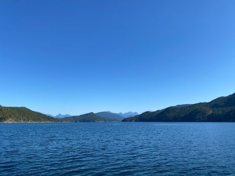 Entrance to Jervis Inlet with Coast Mountains and temperate rainforest on the Sunshine Coast with blue skies, British Columbia, Canada