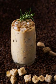 Iced latte coffee. Cup of Iced latte coffee, milk tea on dark coffee seeds background. Could Coffee with cardamom and cinnamon.