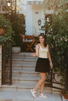 Girl tourist walking through ancient narrow street on a beautiful summer day in MEDITERRANEAN MEDIEVAL CITY , OLD TOWN bUDVA, MONTENEGRO. Young beautiful cheerful woman walking on old street at tropical town. Pretty girl looking at you and smiling