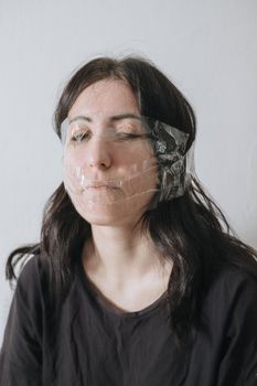 Studio portrait of funny scotch taped woman face on grey background - funny holiday or new year joke