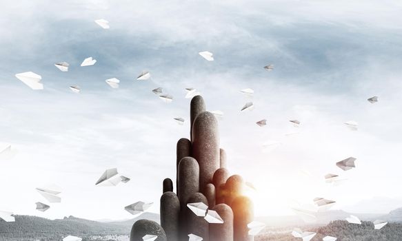 Image of high and huge stone columns located outdoors among flying paper planes with beautiful landscape on background. Wallpaper, backdrop with copyspace.