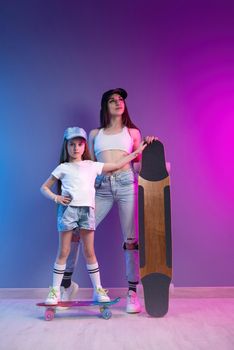 young mother with her daughter on a skateboard and a longboard