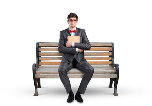 Student sits on a bench, holding a book. Traditional education concept