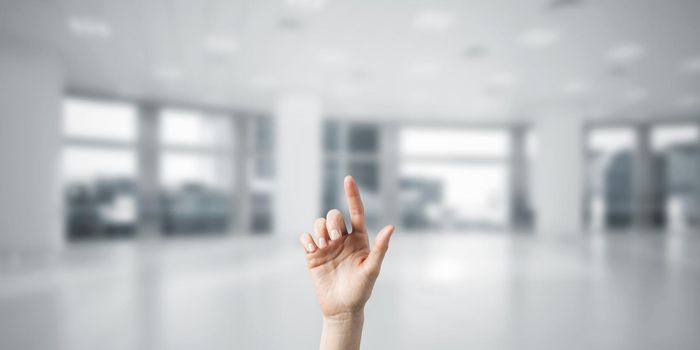 Close of woman hand touching screen with finger and office at background