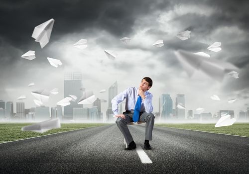 young businessman sits on an office chair, thoughtful and looking up