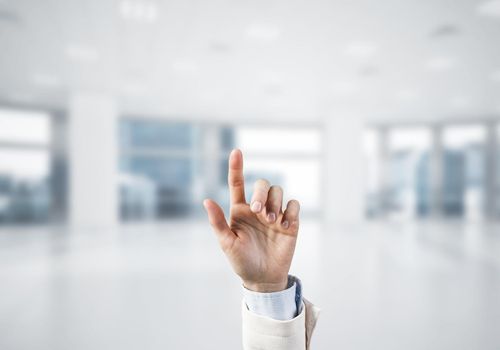 Close of businesswoman hand touching screen with finger and office at background