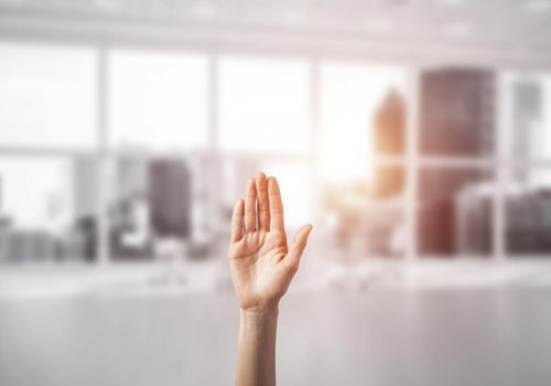 Close of woman hand touching screen with palm and office at background