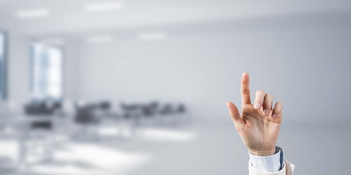 Close of businesswoman hand touching screen with finger and office at background