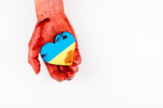 Woman with hands covered in blood holding a heart with the flag of ukraine on a white background. Copy spae