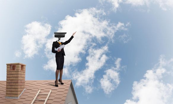 Faceless businesswoman with camera zoom instead of head standing on house roof