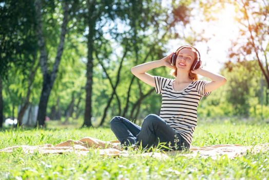 Young attractive woman listens to music in the park. Enjoying music in the park