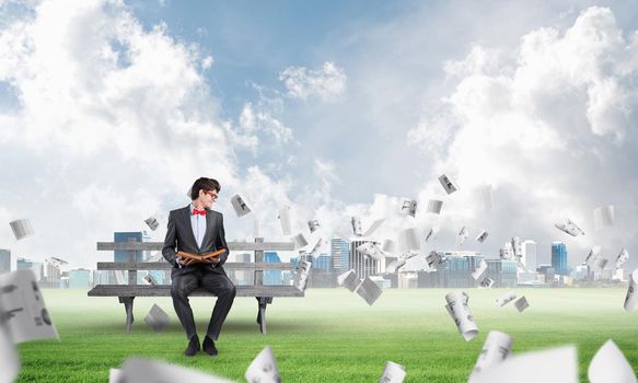 young student with a book on the bench, flying around in the chaos of paper