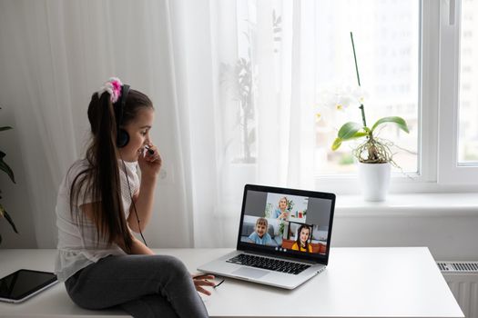 Little girl studying online using her laptop at home.