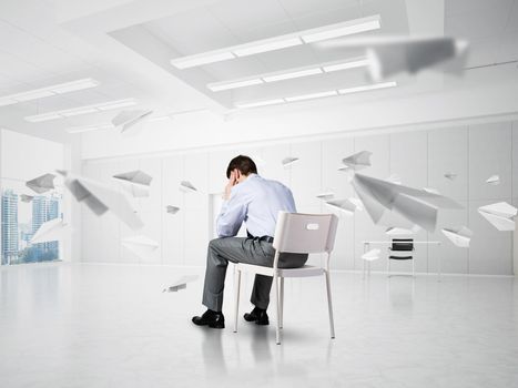 young businessman sitting on a chair with his head in his hands