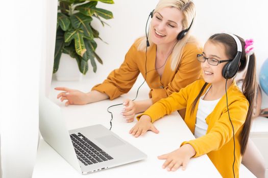 Mother and her girl listening to music on laptop. They sitting in living room. Natural light ambient