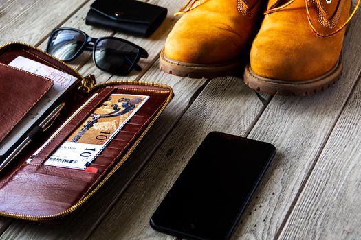 Travel photo. Tracking boot , tickets wallet, smartphone and sunglasses on the wooden background