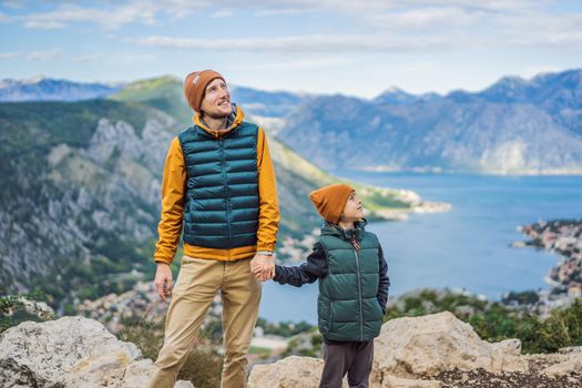 Dad and son travellers enjoys the view of Kotor. Montenegro. Bay of Kotor, Gulf of Kotor, Boka Kotorska and walled old city. Travel with kids to Montenegro concept. Fortifications of Kotor is on UNESCO World Heritage List since 1979.