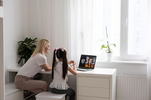 Private lesson. Attentive young woman tutor teacher help little girl pupil with studying math language correct mistakes explain learning material. Smiling mother assist small daughter with home task.