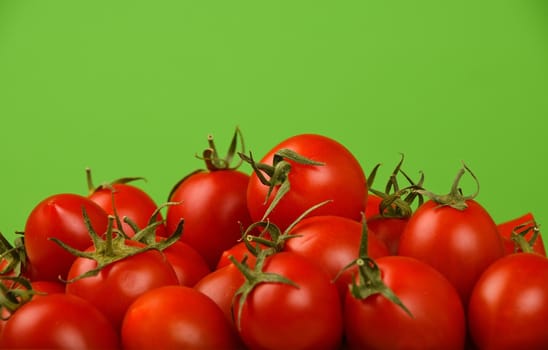 Red ripe fresh small cherry tomatoes over green background close up