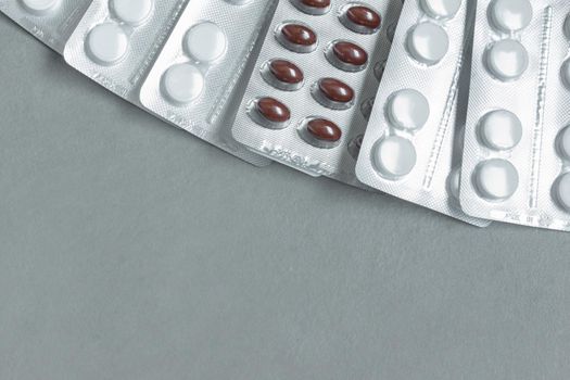 image from above blister packs full of white and red medicine tablets on gray background