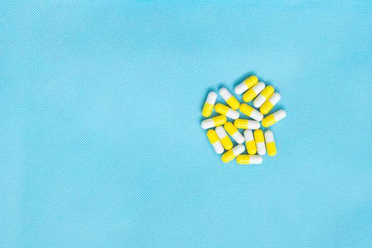 White and yellow pills set flat lay for medicine content with copy space on blue background. Top view of vitamin supplements. Medical concept.