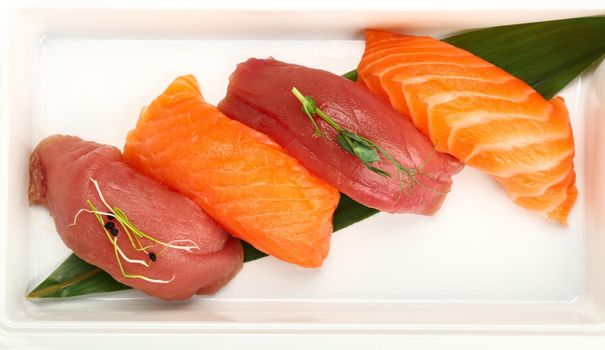 Close up take away set of nigiri sushi with raw salmon and tuna in disposable white plastic tray, elevated top view, directly above