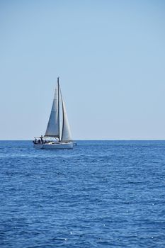 Tranquil seascape with calm sea water ripples and waves and sail yacht under clear day blue sky, high angle view