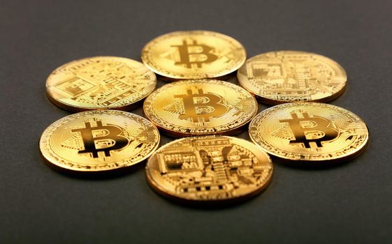 Close up group of golden bitcoin physical coins on black background with copy space, high angle view, selective focus