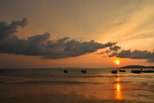 Scenic late sunset sea landscape with traditional Thai longtail boats and dramatic cloudy sky