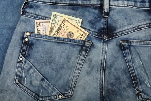 Close up several different value US dollar paper currency banknotes in jeans back pocket, low angle view