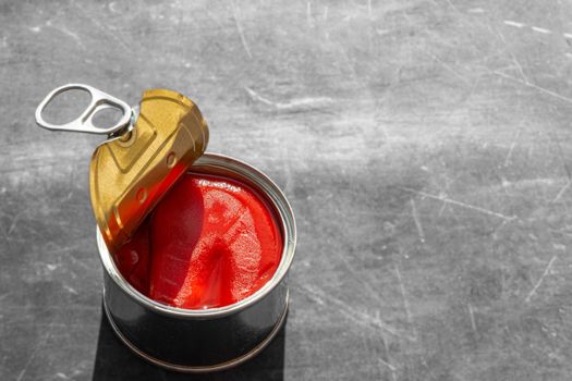 close up of half open red pepper tin can with hard natural light and gray background