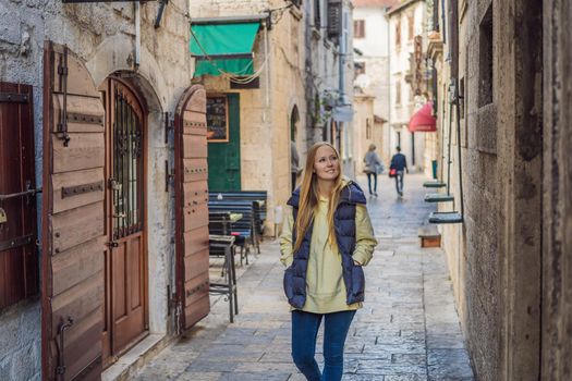 Woman tourist enjoying Colorful street in Old town of Kotor on a sunny day, Montenegro. Travel to Montenegro concept.
