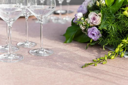 Shot of three crystal glasses with floral center in green and purple tones and negative space with elegant tablecloth with soft light