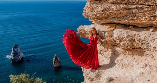 A woman in a red flying dress fluttering in the wind, against the backdrop of the sea