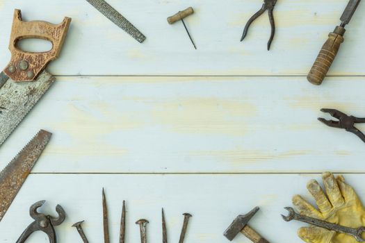 image from above of old tools on light wooden background scattered around image with negative space in center with natural light