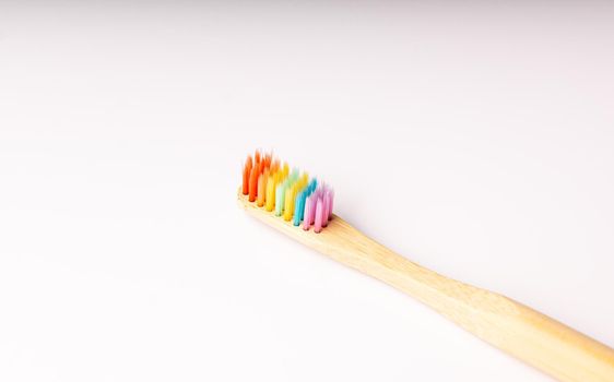 diagonal rainbow wooden toothbrush on white background with soft side lighting