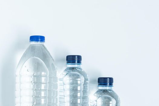 three plastic bottles with blue caps filled with mineral water placed on ladder viewed from above on white background