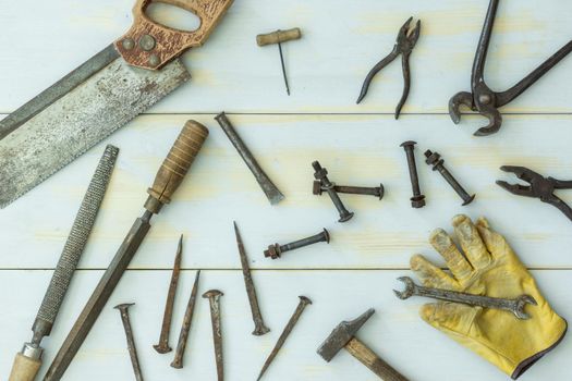 image from above of old tools on light wooden background randomly distributed in natural light