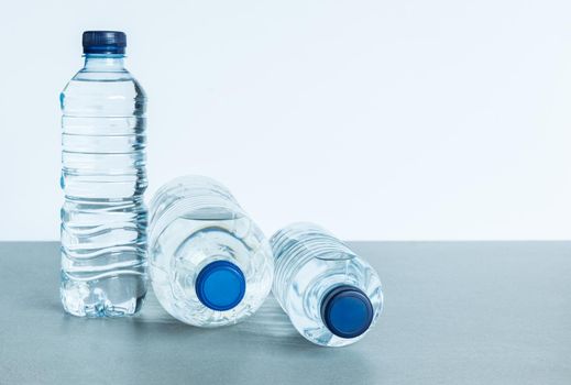three plastic bottles full of mineral water two lying down seen from the front and another small one standing with blue caps on white background