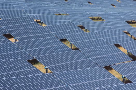 solar panels on a summer day filling almost the entire image except for some gaps through which the terrain can be seen