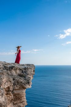 A woman in a red flying dress fluttering in the wind, against the backdrop of the sea