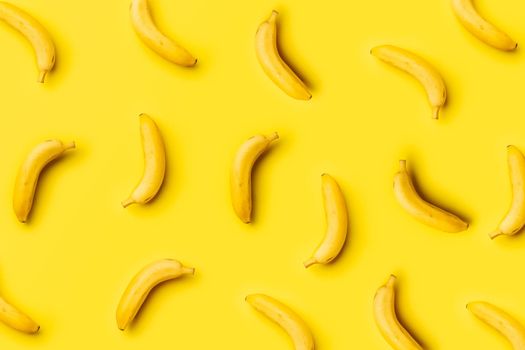 random pattern of ripe bananas on yellow background with soft side lighting